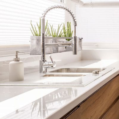 high end kitchen sink and faucet on top of a modern white countertop