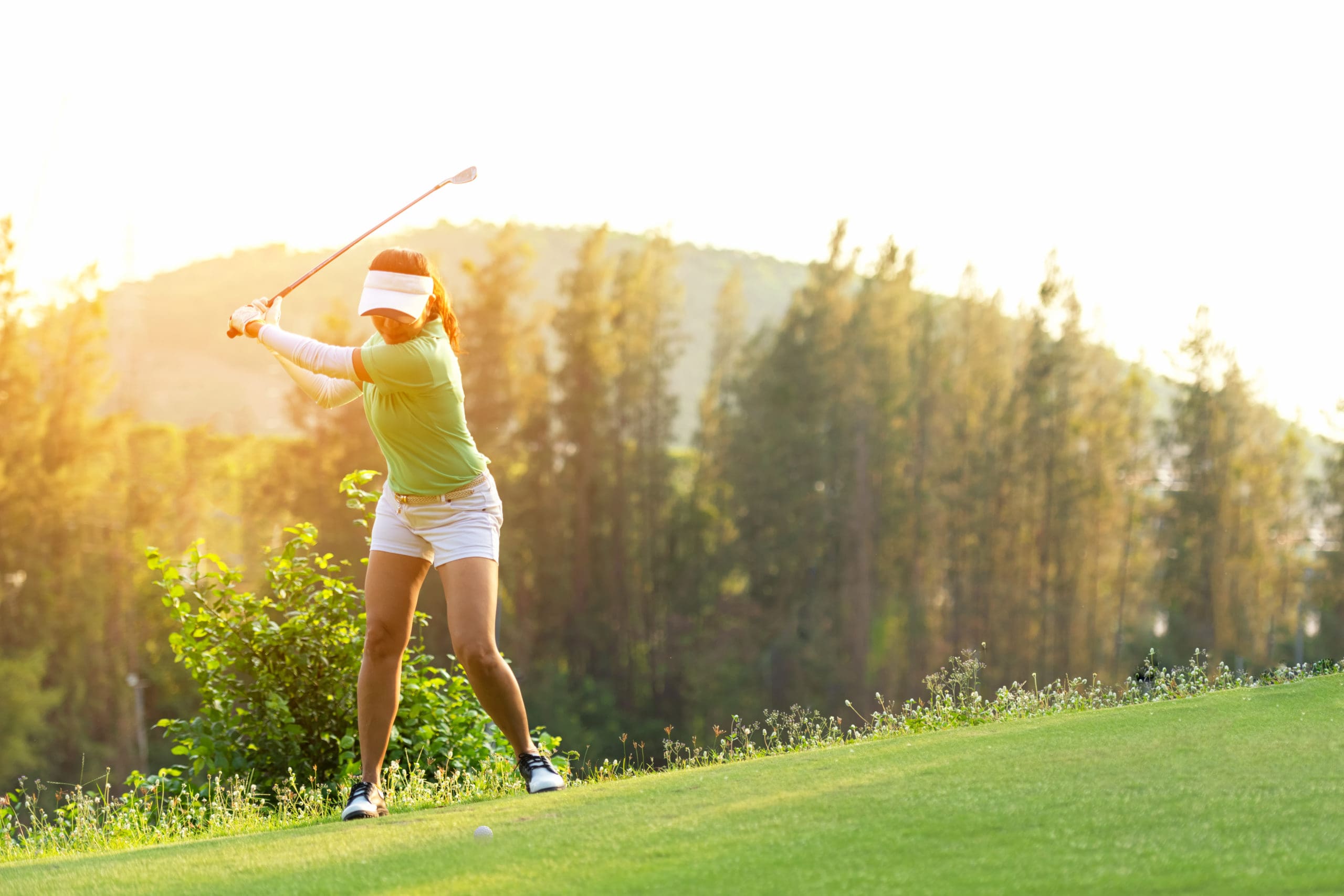 Asian Sporty woman golfer player doing golf swing tee off on the green, people presumably does exercise. Healthy Sport Lifestyle Concept.